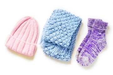 Stylish warm and comfy knitwear. Flat lay winter fashion. Pink wool hat, blue knitted scarf and purple fluffy socks