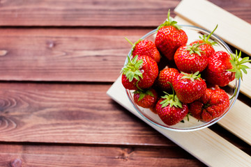 a bunch of ripe Juice strawberries in a bowl on wooden table.Fresh strawberries in basket, freshly harvested fruits on farmer market.healthy food for breakfast and snack.Copy space