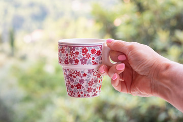 Cheerful cup with coffee in the hand of a woman with pink nail polish