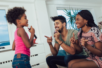 Black family enjoy singing karaoke at home.