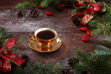 Cup of coffee with gold color on wooden background. New year holiday, Christmas. The concept of holiday and recreation. Bows and Christmas decorations.