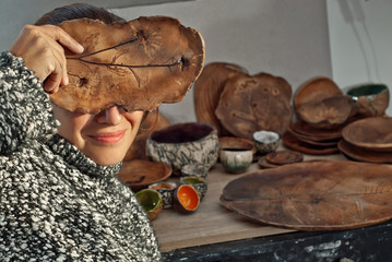 The girl paints pottery. Handmade products on the table at home workshop. Ceramic products with drawings and patterns.
