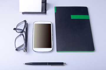 Business concept. Top view of kraft spiral notebook, glasses, smartphone and black pen isolated on background for mockup.