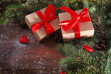 Beautiful bow, gift boxes and fir branches with cones on a wooden background. New year and Christmas holidays. red heart. Valentine's day.