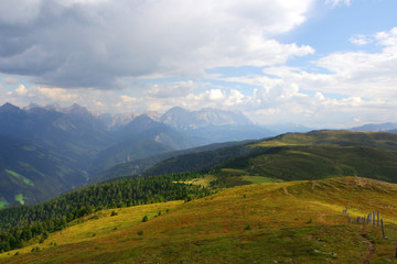 Hike and relax on top of a mountain and enjoying valley view during trip in the alps with sun beam between clouds.