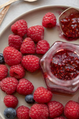 Raspberry jam in jar with raspberry and blueberry near