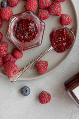 Raspberry jam in jar with raspberry and blueberry near