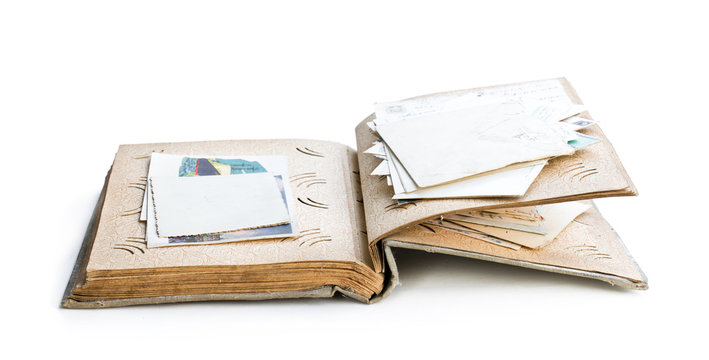 Old photo album with photos and post cards isolated on white