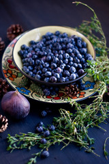 Blueberries on the plate with figs and herbs on the Brown wooden background