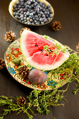 A piece of watermelon with Blueberry and herbs on wooden background