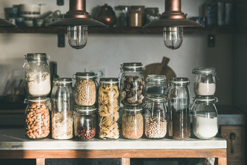 Rustic kitchen food storage arrangement. Grains, cereals, nut, dry fruit, flour, pasta kinds in...