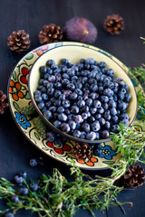 Blueberries on the plate with figs and herbs on the Brown wooden background