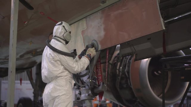 Painting the aircraft at the factory. The engineer repairing the aircraft. Maintenance of passenger aircraft. Repair of an aircraft wing. Passenger plane in the hangar in the repair. 4K