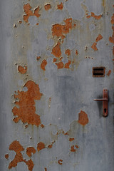Old metal door with peeled paint and rust.
