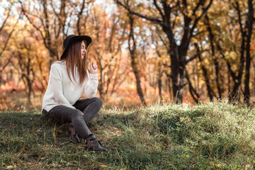 beautiful woman sitting on grass on sunny autumn day.