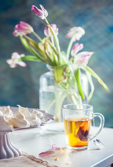 Cup of tea and meringues with bouquets in the background