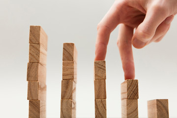Persons hand walking up a set of wooden blocks. Business development and growth concept