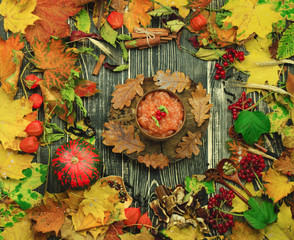 Apple jam and autumn leaves on old wooden table background