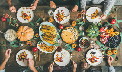 Vegan or vegetarian Thanksgiving, Friendsgiving holiday celebration. Flat-lay of friends eating...