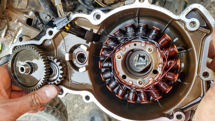 Broken alternator from motorcycle engine in hands from oil
