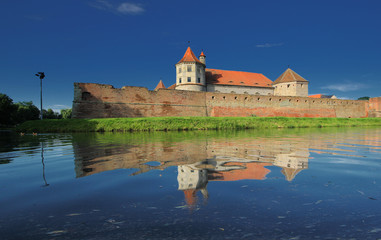 Naklejka na ściany i meble Fagaras fortress with its red stone walls under the deep blue sky mirrored in