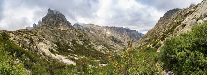 Panoramic view of the Restonica valley in front of Lombarduccio, a 2261m high mountain in Corsica. La Restonica river can be seen flowing down from Lac de Melo and is a popular tourist hiking route.