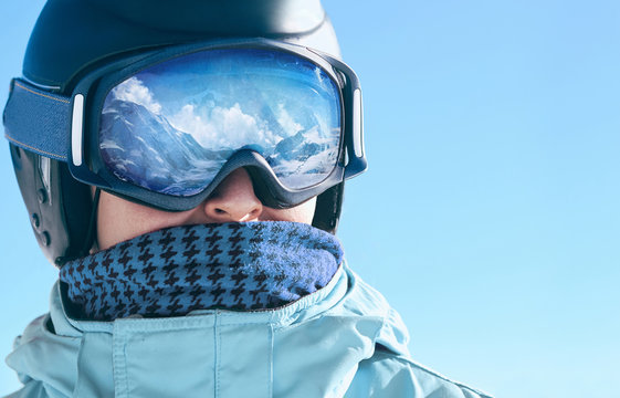 Close up of the ski goggles of a man with the reflection of snowed mountains.  A mountain range reflected in the ski mask.  Portrait of man at the ski resort.  Wearing ski glasses. Winter Sports.
