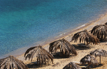 Exotic tropical beach with palm leaves umbrellas, fine sand, clear turquoise 