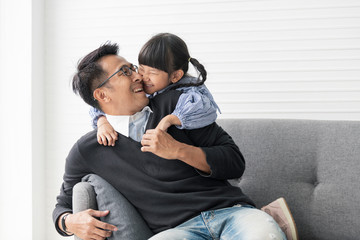 Asian father and daughter playing and kiss together in livingroom at home.