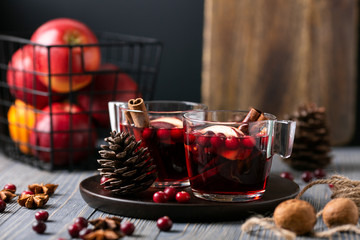 Mulled wine in glasses on a wooden background. Apples, cranberries, cinnamon, star anise, walnuts, cones