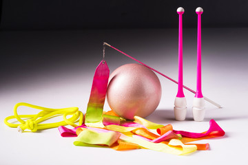 Accessories for rhythmic gymnastics ball, clubs, ribbon, rope lie on the floor. White background