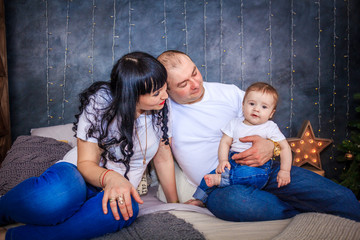 Naklejka premium Parents with the son sit on a bed. Family photo.