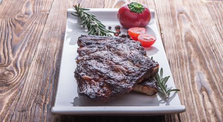 baked ribs on white plate with tomatoes and spices