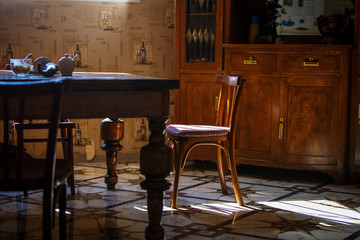 Retro interior in the dining room of Georgia hostel. The old table and chair is illuminated by rays of light from the window, made of brown wood.