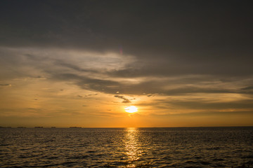 Fototapeta na wymiar Bright sunset with large yellow sun under the sea surface. Sunset over sea landscape. Beautiful sunset with sky over calm sea in tropical island