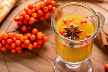 Hot beverage of sea-buckthorn berries in glass cup. Rustic style.