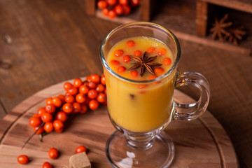 Hot beverage of sea-buckthorn berries in glass cup. Rustic style.