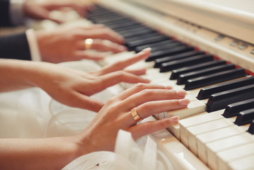 Fototapeta premium hands of the newlyweds play the piano wedding day, melody, rings