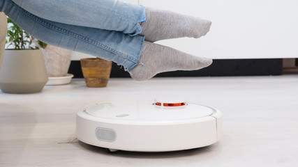 girl resting at home on the couch, while the robot vacuum cleaner. Time for yourself. smart House.