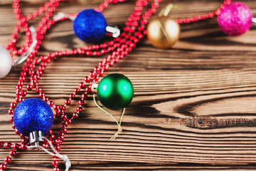 Lot of colorful christmas balls and red beads on thread on old weathered brown table