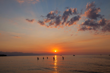 Fishermen draw up a net to catch fishes on the beach iat sundown