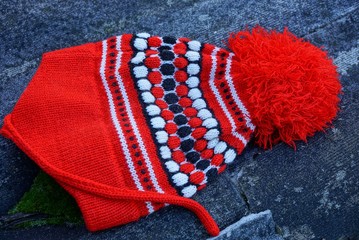 colored wool hat with a pompon lies on gray asphalt