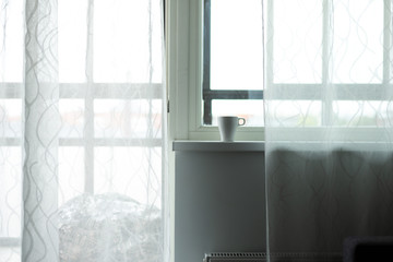 A cup of coffee on the windowsill. Big window. Scandinavian style