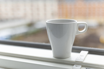 A cup of coffee on the windowsill. Big window. Scandinavian style