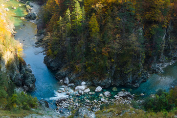 Drying up blue river flows deep in the canyon against the autumn forest.