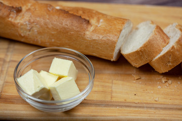 Sliced baguette and butter on wooden Board