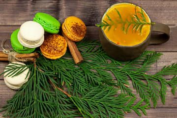 Hot berry tea with macaron and Christmas tree on wooden background top view