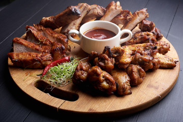 Roasted sliced barbecue pork ribs with chicken wings and aromatic herbs and souce