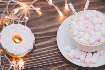 hot chocolate with marshmallow candy and Christmas decorations in the form of a donut on a wooden background