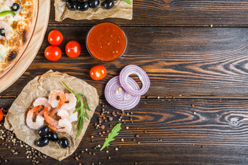 Macro. Food background design. Seafood, shrimps and olives on a dark wood. Pizza ingredients.